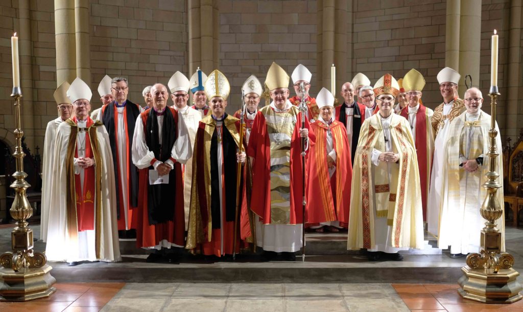 Large group of bishops wearing robes in front of a Cathedral high altar