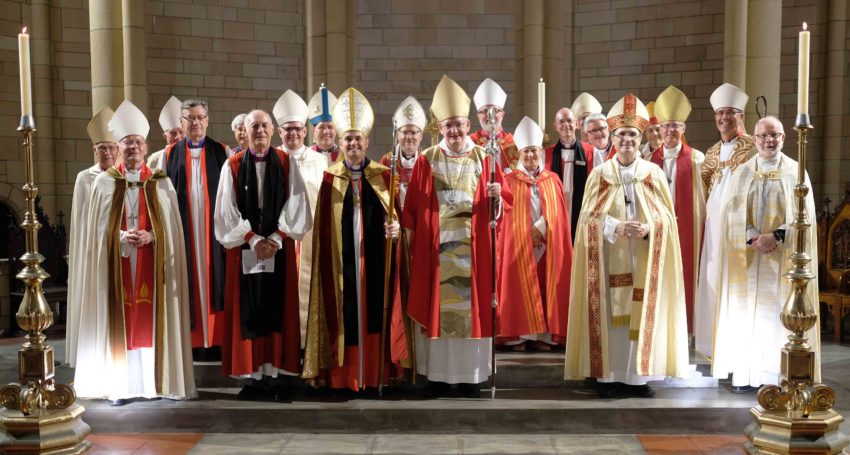 Large group of bishops wearing robes in front of a Cathedral high altar