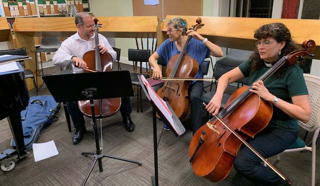 Three people playing cello