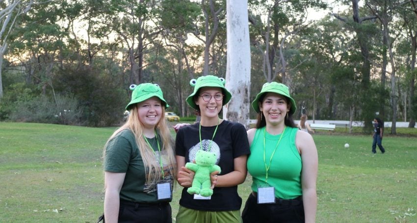 Sarah Warburton, Sophia Colledge and Amy Stalley, co-dorm leaders for the green frogettes dorm holding their mascot, at Senior Ichthus in 2023