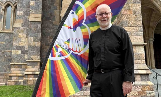 The Very Rev'd Dr Peter Catt with a rainbow flag outside St John's Cathedral in December 2023