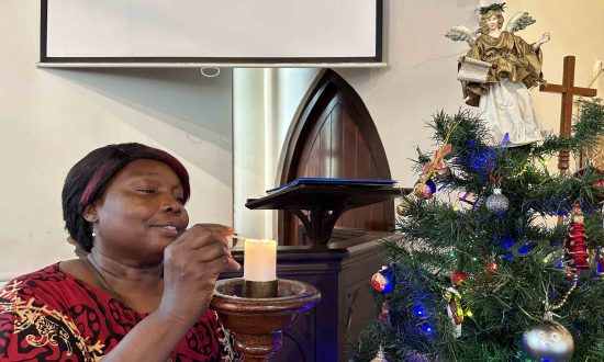 The Rev'd Rebecca King lighting a candle near a Christmas tree