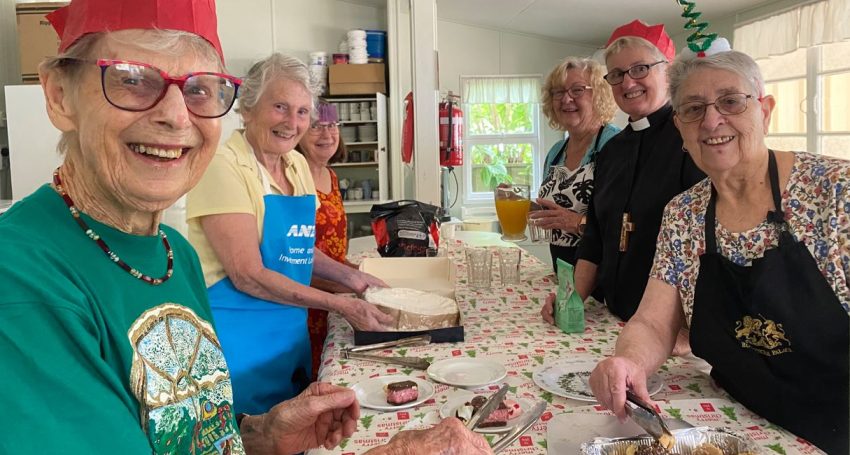 A woman priest and women parishioners serving Christmas treats around a table