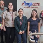 Five Anglicare workers in front of Anglicare sign