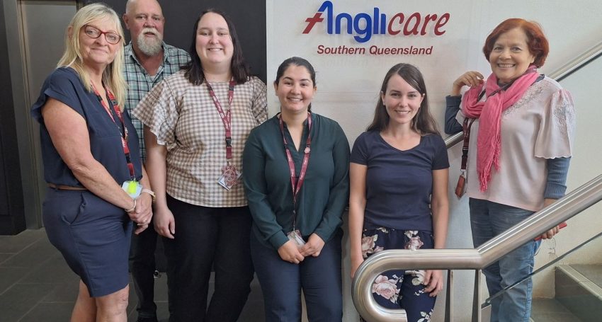 Five Anglicare workers in front of Anglicare sign