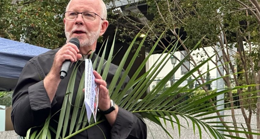 Anglican priest holding a palm on Palm Sunday with a microphone in hand