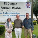 Three faith leaders standing in front of a church sign