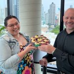 Woman and man in office lunchroom holding chocolate Easter cupcakes