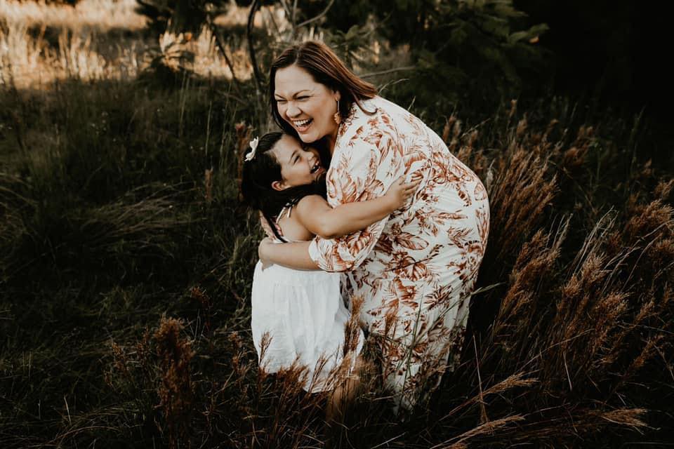 Mother and daughter hugging in a field 