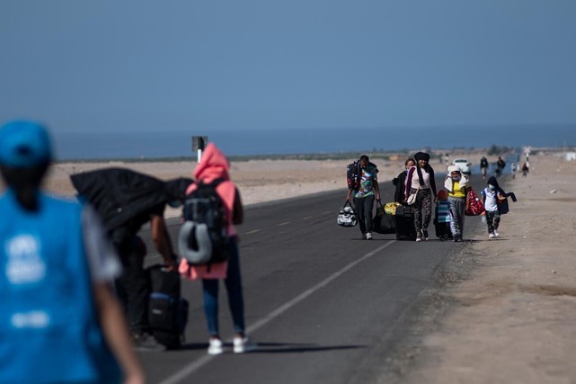 A Venezuelan family walking along the highway that runs parallel to the border with Chile