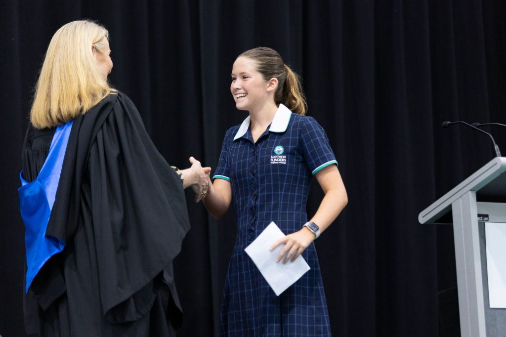Student and principal shaking hands on a stage 