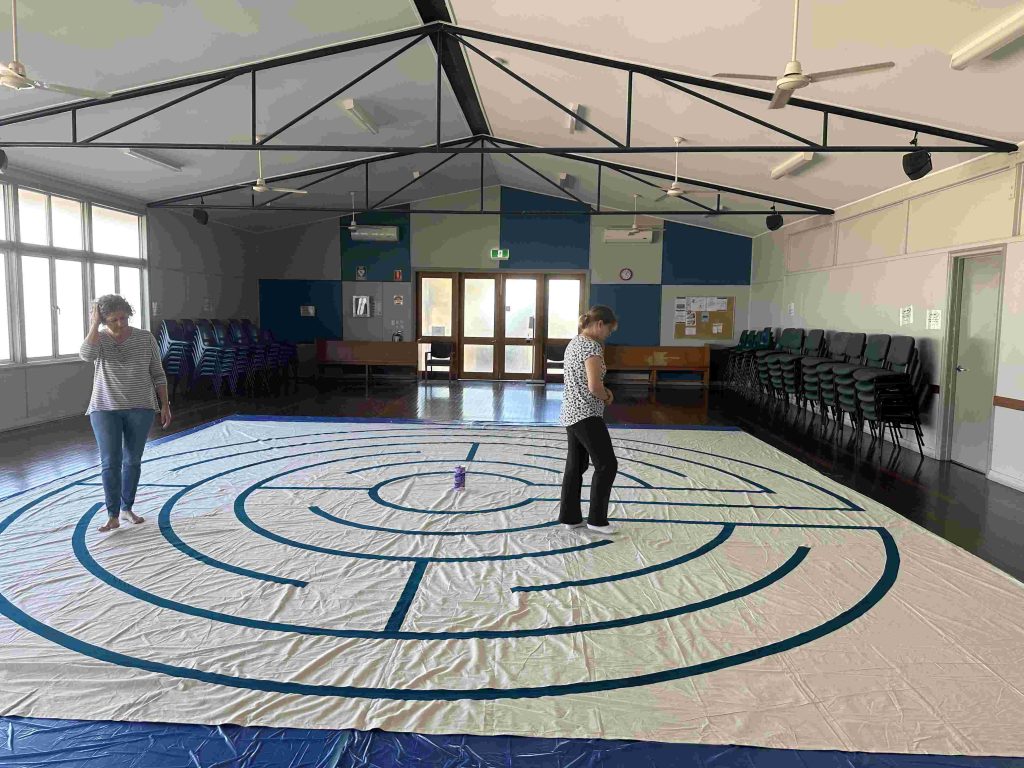 Two women walking a labyrinth in a church hall 