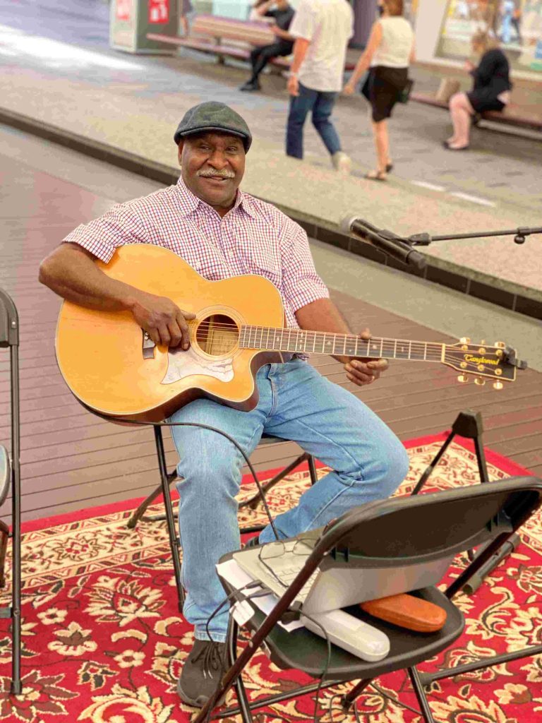 Torres Strait Islander man playing guitar in the city