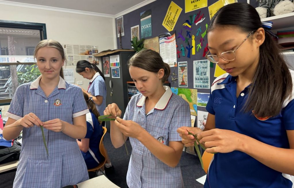 Teenage school students in uniform making palm crosses