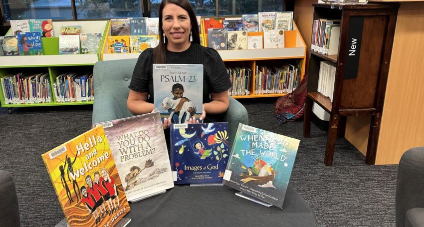 Woman sitting in a library surrounded by kids' books