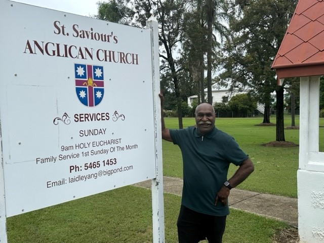 Torres Strait Islander man leaning against a church sign 