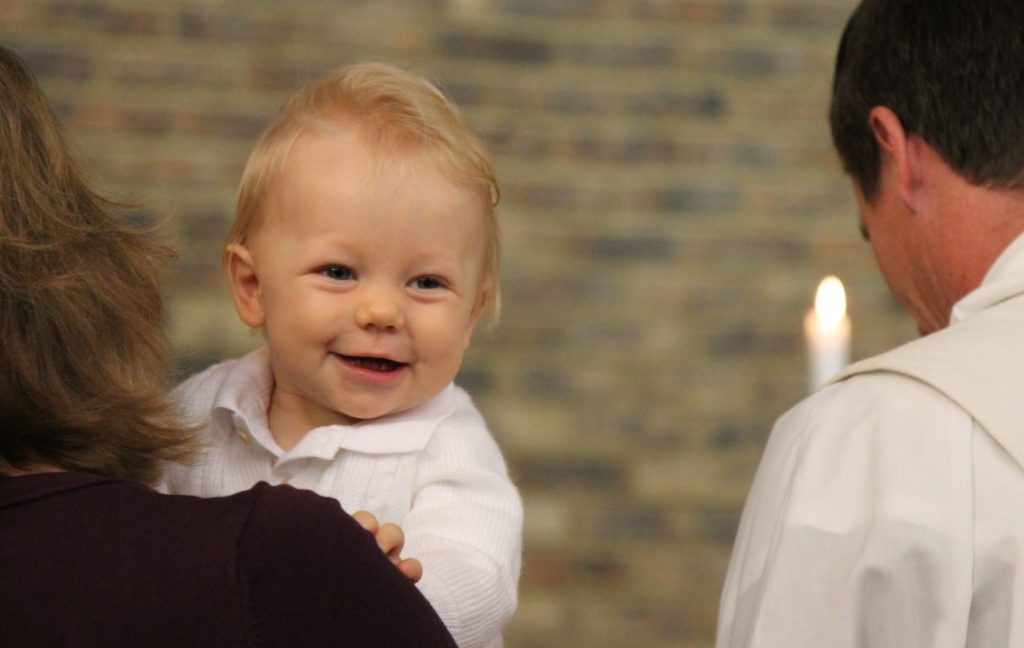A baby wearing white at his baptism 