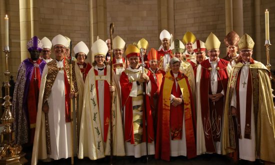 Large group of Anglican archbishops and bishops gathered in the sanctuary area of a cathedral high altar