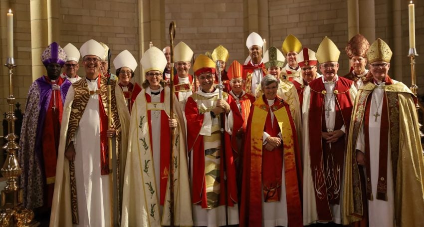 Large group of Anglican archbishops and bishops gathered in the sanctuary area of a cathedral high altar