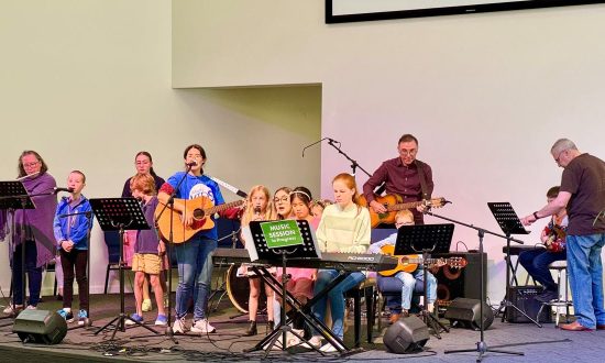 Adults and children playing instruments and singing in a modern church