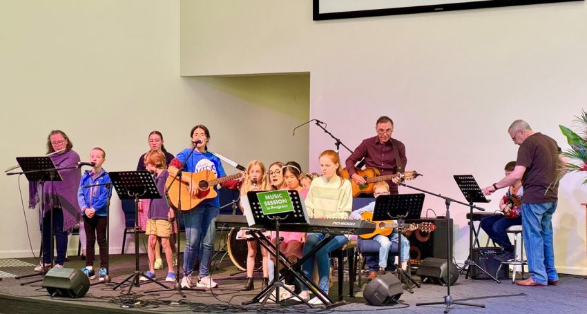 Adults and children playing instruments and singing in a modern church