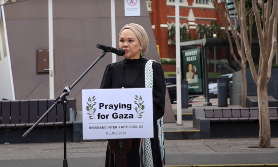 Muslim woman reading at a prayer vigil outside