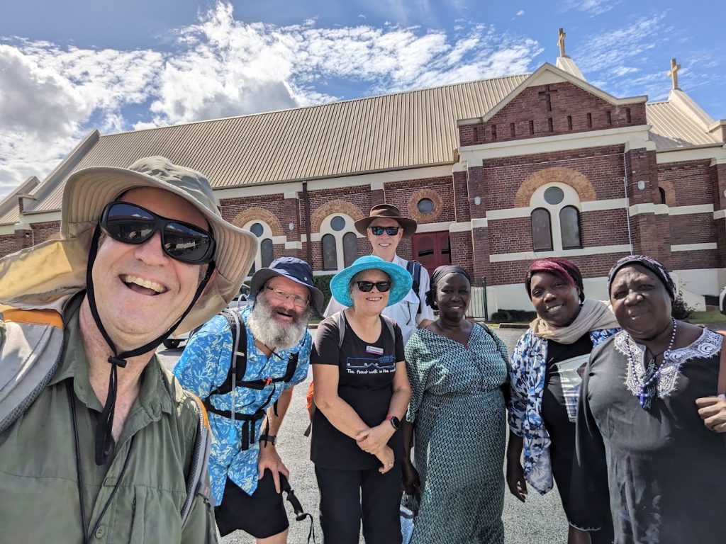A group of people of diverse ethnicities walking outside a church and smiling 