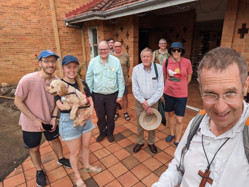 Parishioner, clergy and a dog outside a church ready to start a long walk