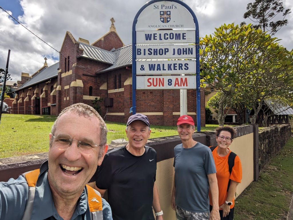 Four people standing next to a church sign outside 