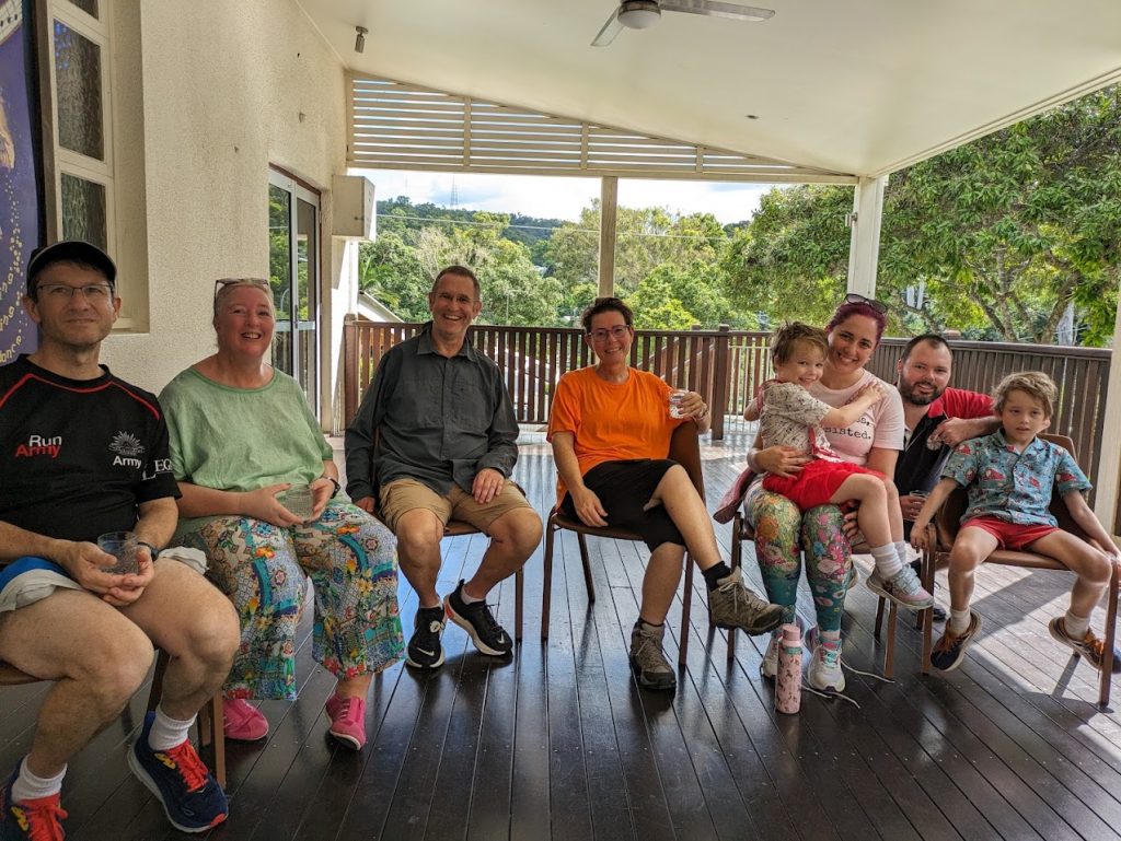 Six adults and two children sitting on chairs on a deck