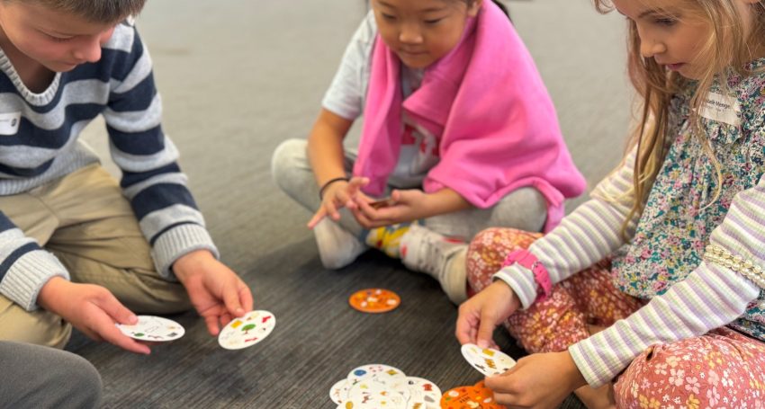 Children playing SEEK card game on floor