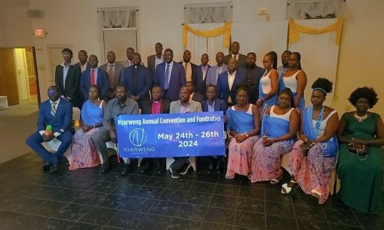 Group of South Sudanese people holding up a blue event banner