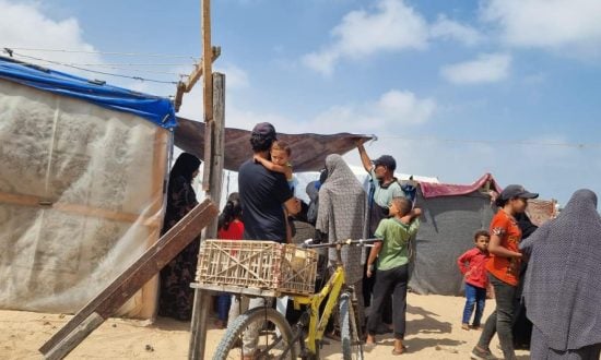 Palestinian refugee men, women and children outside makeshift shelters