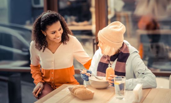 Older homeless woman enjoys conversation with young woman while having a meal