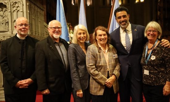 Six people in front of a cathedral sanctuary smiling while looking at the camera