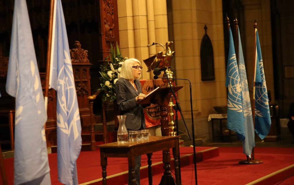 Woman in grey suit giving a lecture in front of a Cathedral sanctuary