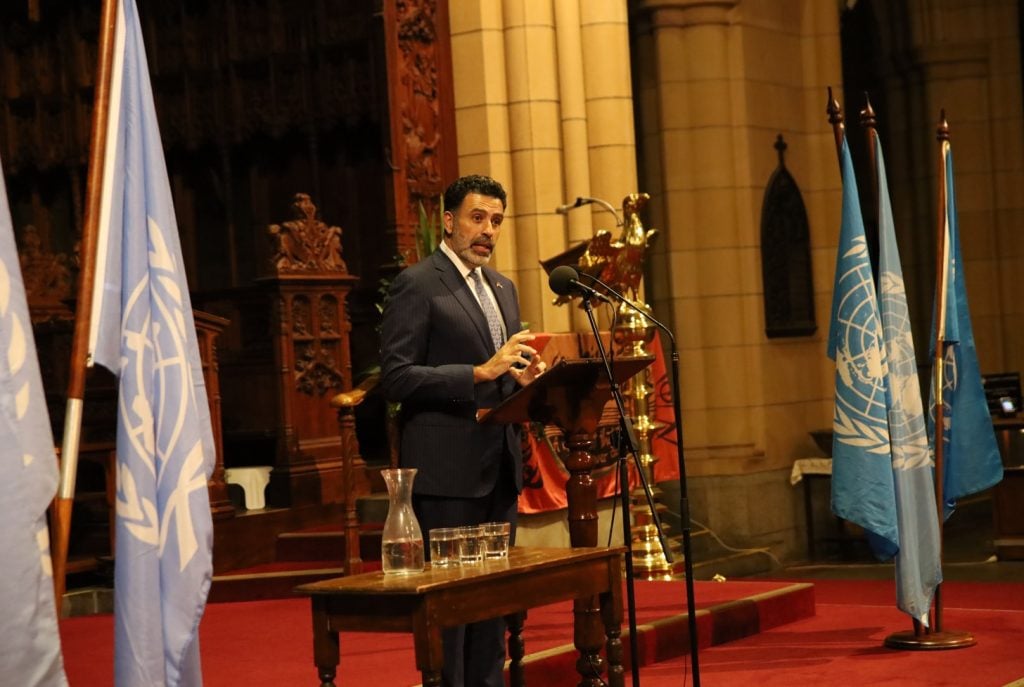 Man in dark suit giving a lecture in front of a Cathedral sanctuary