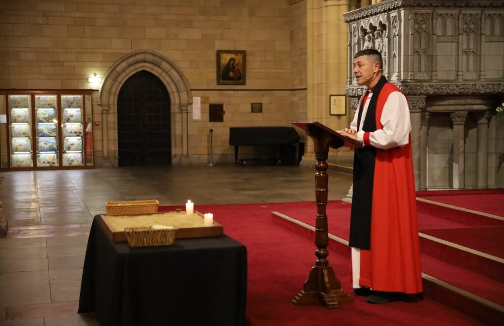 Archbishop in robes in front of a lectern and candles