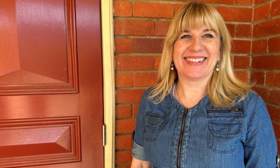 Woman wearing a denim dress standing in front of a red brick wall