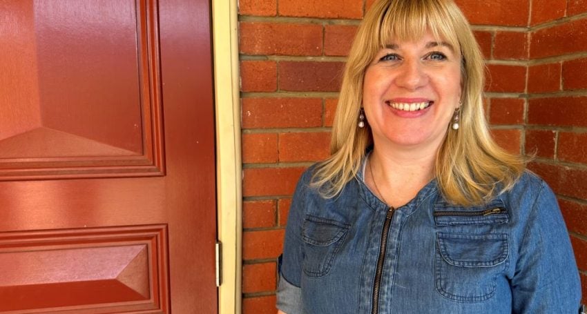 Woman wearing a denim dress standing in front of a red brick wall