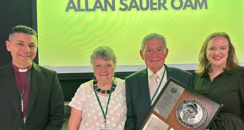 Two men and two women in front of a green screen with a man holding an award