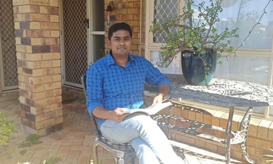 Man in blue shirt reading a book in a courtyard