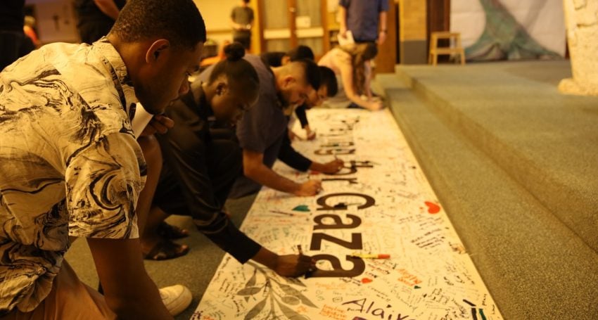 Inter-faith young people signing a prayer banner for Gaza