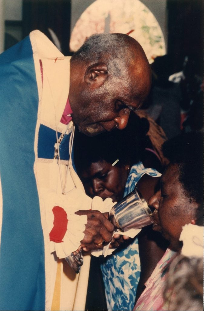 Torres Strait Islander bishop offering the communion cup to a parishioner in a church