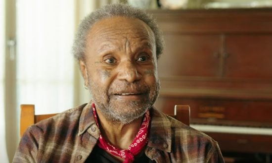 Torres Strait Islander elder wearing a brown check shirt and red neck scarf