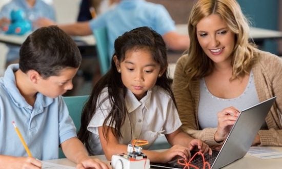 Two children and a teacher at a desk