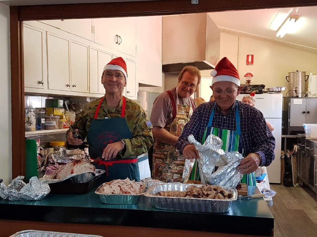 Three men serving in a church kitchen on Christmas Day 