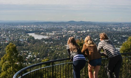 Three young people looking over Brisbane from a lookout point during the day