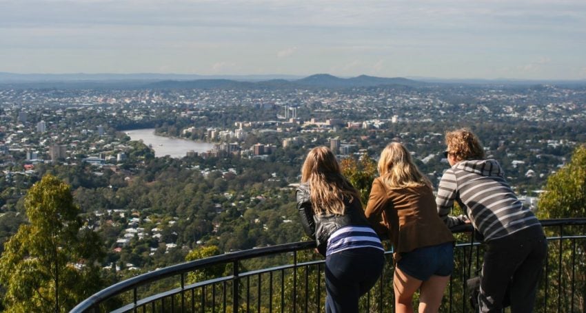 Three young people looking over Brisbane from a lookout point during the day