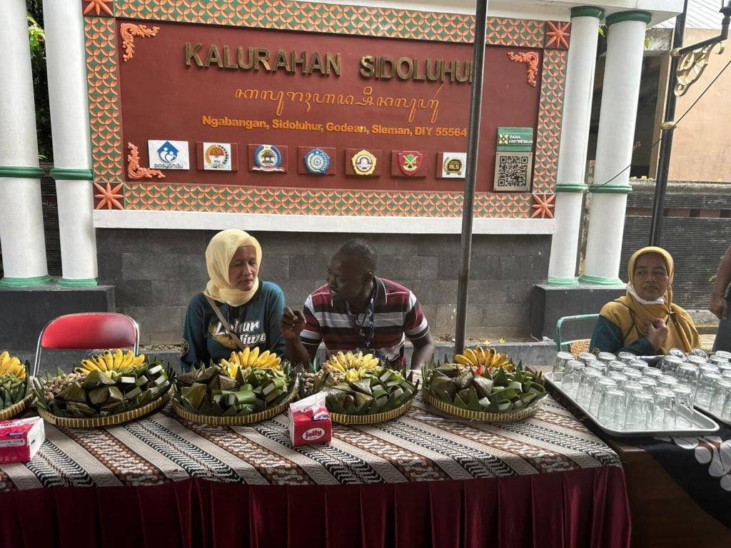 CEO sitting between two women in Indonesia with rice wrapped in banana leaves on the table in front of them